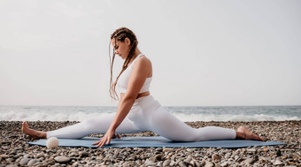 女人海瑜伽中间岁的女人辫子长发绺白色紧身裤上衣伸展运动普拉提瑜伽席海女健身瑜伽例程概念健康的生活方式