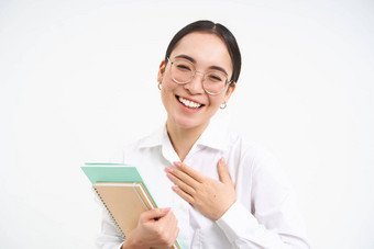 友好的快乐亚洲女人眼镜老师把手胸部微笑介绍了站白色背景