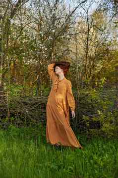 优雅的复杂的女人提出了放松站柳条栅栏别墅长橙色衣服持有头发手