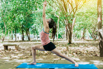 年轻的女人瑜伽战士构成女孩练习维拉巴德拉萨那瑜伽在户外