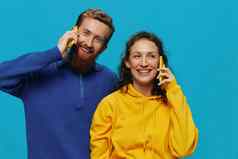 女人男人。快乐的夫妇手机手弯曲的微笑快乐的蓝色的背景概念真正的家庭的关系会说话的电话工作在线