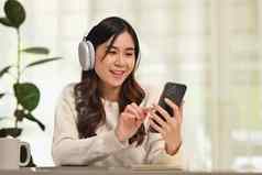 快乐千禧女人穿现代无线耳机智能手机人技术生活方式