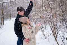 年轻的夫妇走公园冬天的家伙女孩拥抱在户外