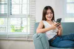快乐年轻的女人放松消息传递智能手机
