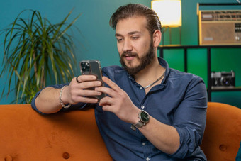 黎巴嫩阿拉伯男人。坐着沙发智能手机分享消息社会媒体应用程序