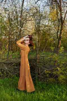 优雅的复杂的女人提出了站柳条栅栏别墅长橙色衣服矫直头发手