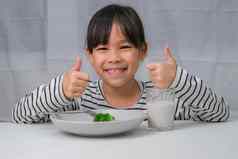 可爱的亚洲女孩喝玻璃牛奶早....学校女孩吃健康的蔬菜牛奶餐健康的食物童年