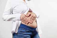 上腹部怀孕了女人持有手只肚子使心形状孤立的白色背景