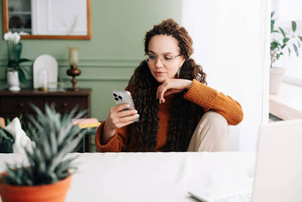 时尚的女人浏览智能手机首页在线购物年轻的女人穿眼镜检查应用程序手机首页快乐女人智能手机在线购物浏览