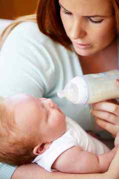 成长大强大的年轻的妈妈。奶瓶喂养新生儿