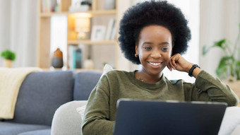笑非洲式发型女人移动PC看有趣的喜剧电影视频微笑快乐女人时尚的时髦的很酷的头发坐着首页生活房间沙发放松技术