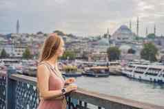 年轻的旅游女人加拉塔桥金角湾伊斯坦布尔全景城市景观著名的旅游目的地横跨博斯普鲁斯海峡海峡通道旅行景观博斯普鲁斯海峡火鸡欧洲亚洲