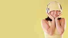 时尚音乐耳机女人肖像模型空间孤立的黄色的背景脸快乐亚洲女孩模型科技听音频声音播客广告工作室