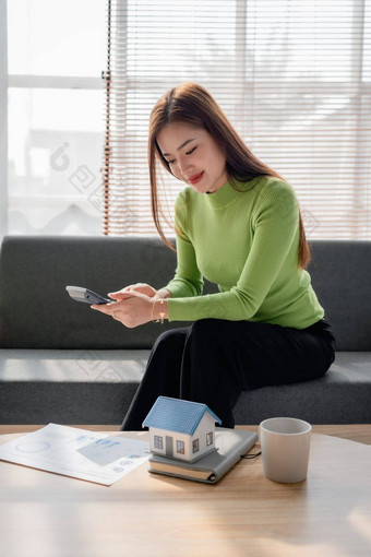 女人坐着舒适的沙发规划计算费用抵押贷款计算器首页桌子上保险预算住宅贷款住宅业务财产概念