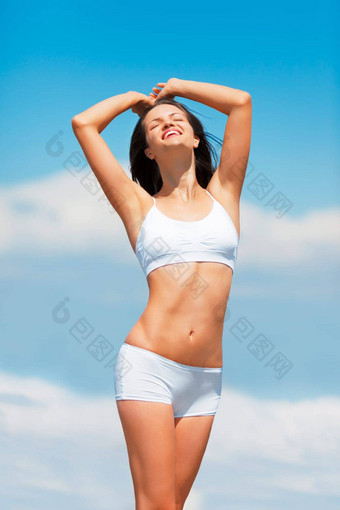 蓝色的天空年轻的女人快乐身体伸展运动内衣爱女人微笑自由无忧无虑的身体护理健康健康模型内衣护肤品在户外