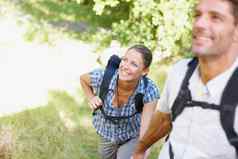自然使快乐年轻的夫妇背包持有手走公园