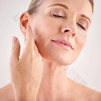 脸美护肤品高级女人工作室灰色的背景自然抗衰老的治疗面部皮肤护理健康有吸引力的成熟的女模型触碰脸颊