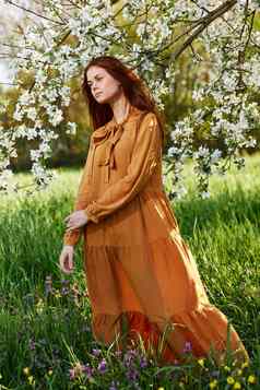 明亮的垂直照片有吸引力的女人长橙色衣服站开花树阳光明媚的温暖的天气