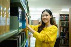 有吸引力的亚洲学生女人采取教科书架子上研究图书馆教育学习青年生活方式概念