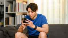 千禧亚洲男人。发短信消息聊天社会智能手机沟通人技术概念