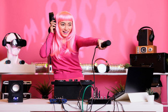 <strong>快乐音乐</strong>家粉红色的头发玩电子音乐转盘持有麦克风球迷