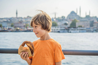 男孩伊斯坦布尔早餐simit玻璃土耳其茶玻璃土耳其茶百吉饼simit金角湾伊斯坦布尔火鸡突厥语旅行孩子们概念