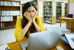 疲惫年轻的学生女人坐着图书馆移动PC痛苦头疼感觉抑郁