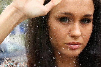 肖像年轻的女人窗口雨