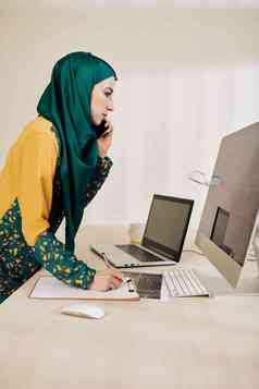 皱着眉头穆斯林女商人阅读文章电脑屏幕会说话的电话客户端