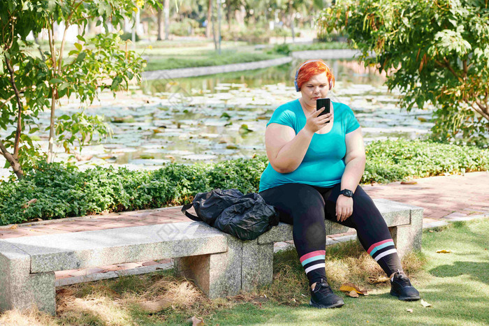 大小年轻的女人坐着板凳上公园听音乐智能手机