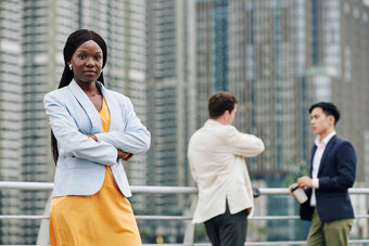 自信黑色的年轻的女商人站在户外穿越武器相机同事讨论工作背景