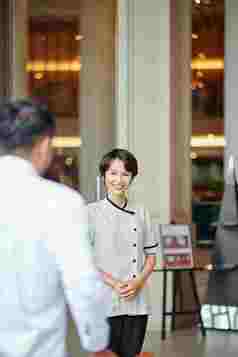 微笑年轻的亚洲礼宾部男人。进入酒店游说团体