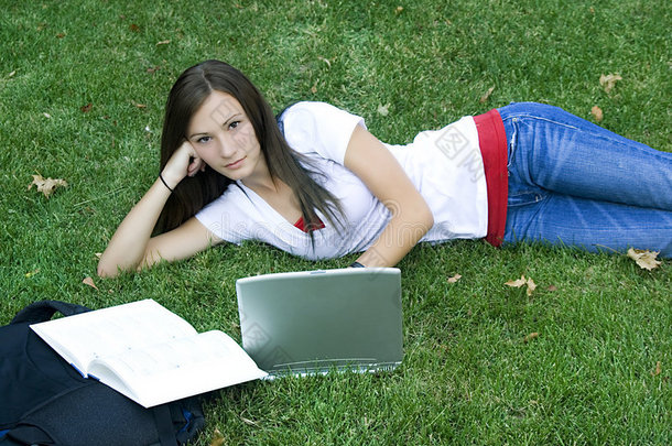 可爱的少女躺在草地上学习