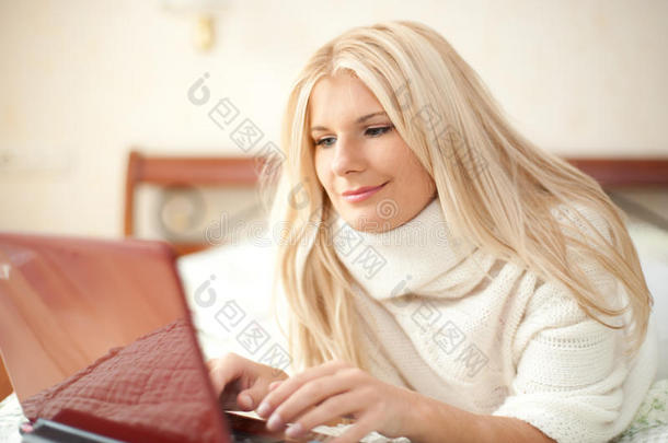 床上拿着笔记本电脑上网聊天的年轻女子
