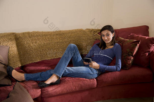 在沙发上放松发短信的漂亮少女