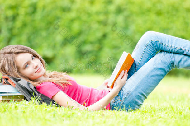 快乐的女学生躺在草地上<strong>翻开</strong>书本