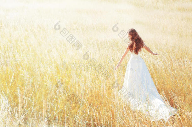 夏日漫步在阳光灿烂的草地上的女人