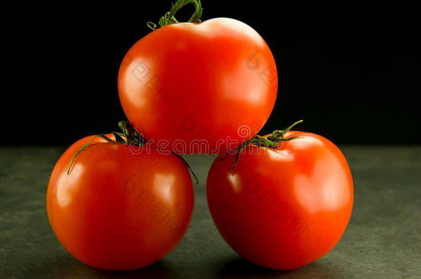 <strong>黑灰</strong>色背景上的三个堆叠的西红柿