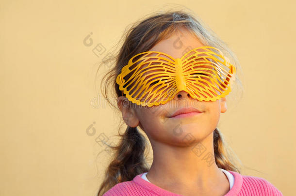 快乐女孩把脸藏在蝴蝶面具后面