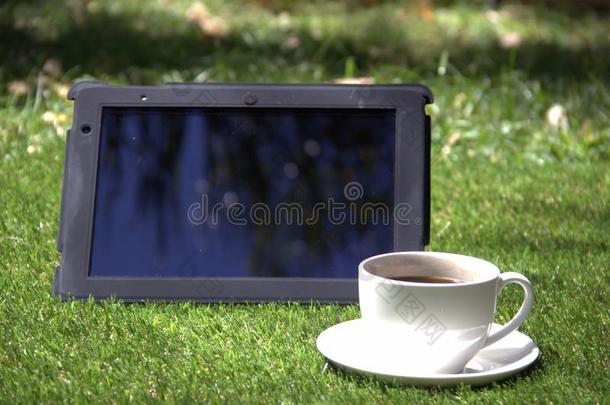 平板电脑和一杯咖啡在草地上