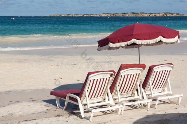 沙滩上的三个躺椅和雨伞