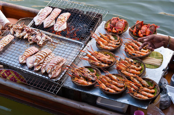 泰国传统水上市场出售新鲜鱿鱼和大虾的船。