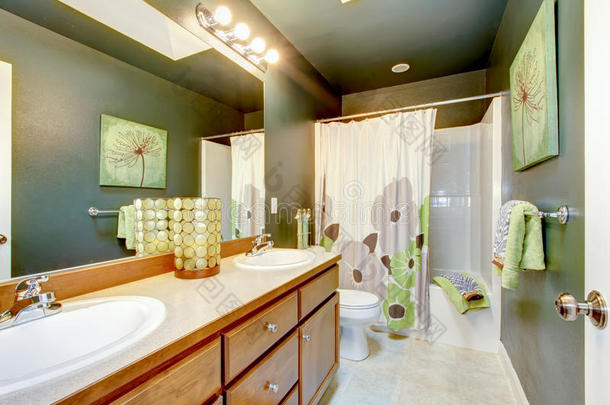 带木质橱柜和淋浴浴缸的绿色浴室。