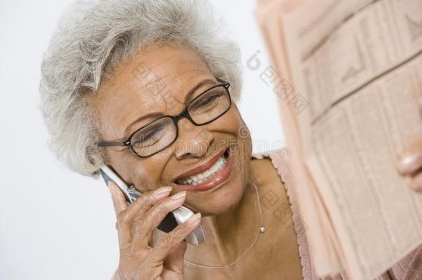 在报纸上研究股票和股票的快乐的老太太