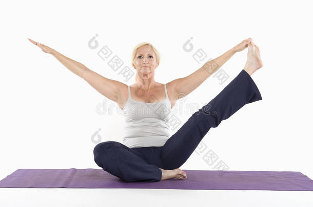 成熟的女人坐在垫子上<strong>伸展</strong>双臂做瑜伽