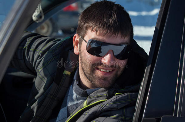 一个在私家车上戴太阳镜的年轻人