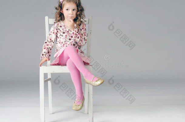 可爱体贴的小女孩坐在白色的椅子上，很多