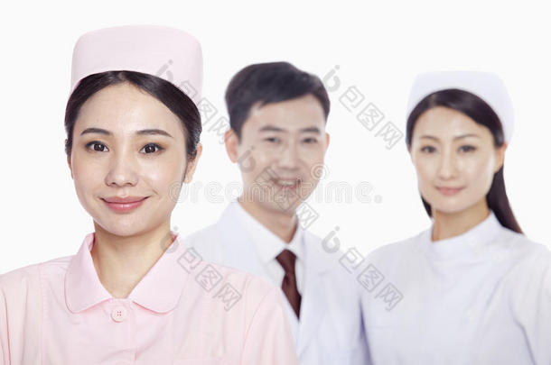 微笑的年轻护士的肖像，医生和护士在背景中，摄影棚拍摄
