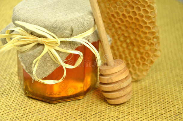 一罐新鲜可口的蜂蜜，带蜂巢和蜂蜜勺