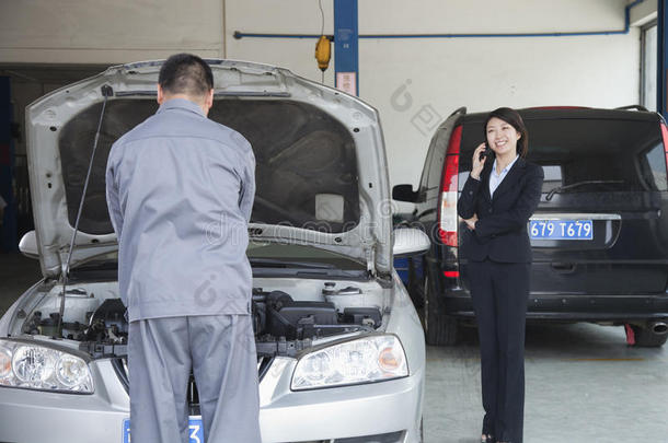 一个女人一边打电话一边<strong>修</strong>车